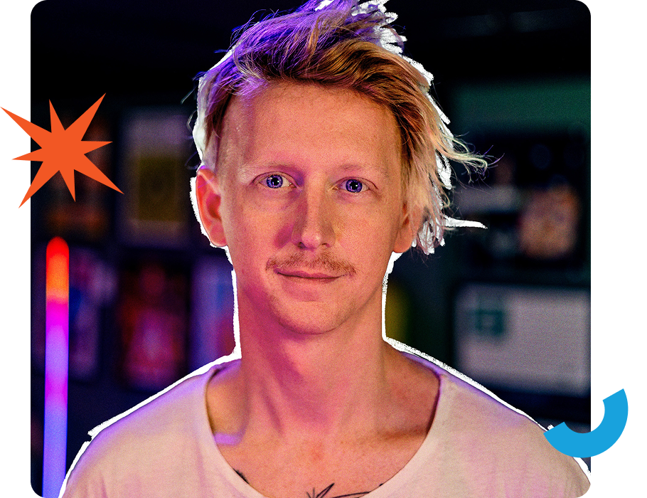 A person with light-colored hair and a white top stands against a blurred background featuring neon lights and abstract shapes.